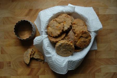 Peanut butter and honey dog treats sitting in a paper towel and basket, with a cookie cutter, on a chopping board.